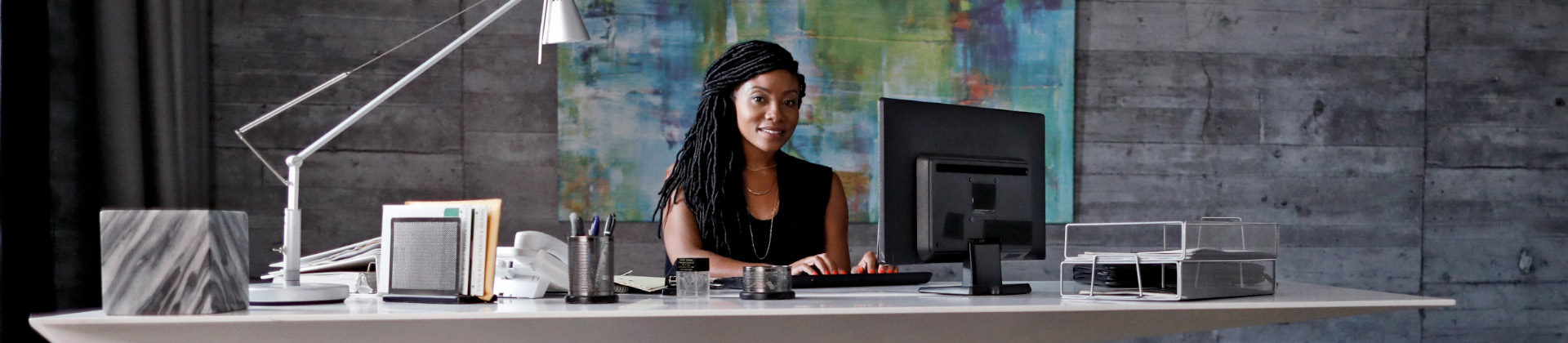 Asya W. sits behind a desk working on a computer