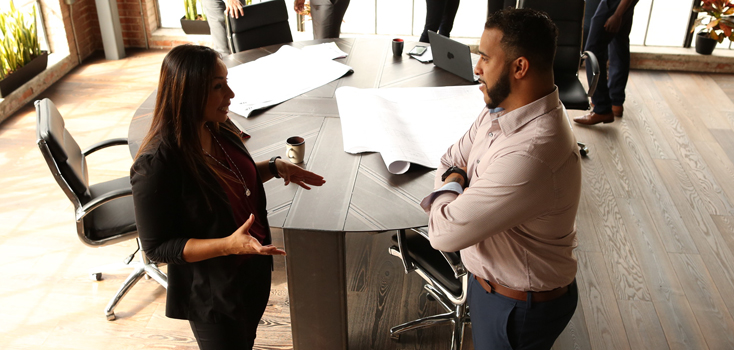 a man and a woman talk in a meeting next to a desk