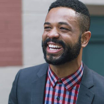 a man in a suit smiles warmly