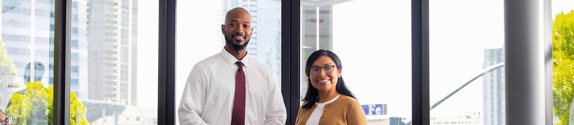 Teddy T. and Cecilia M., NU students, smile in front of a glass window