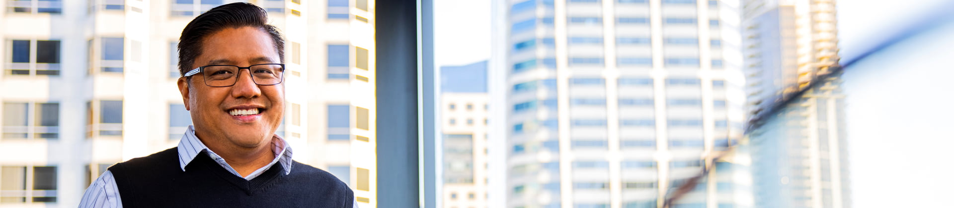 Edward H. stands in front of a glass window with a skyline view.