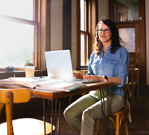 woman smiles at a desk with a laptop