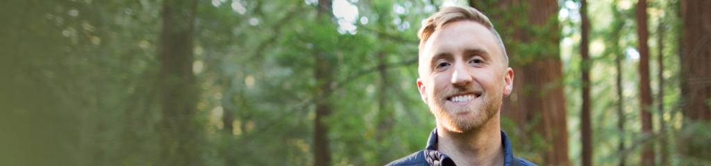 man outside in forest smiling at camera