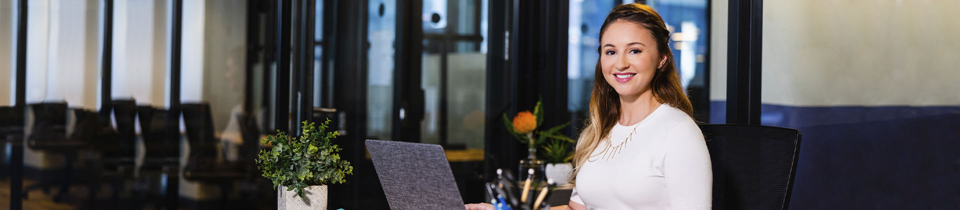 Woman with a laptop smiles in a lobby, ready to greet people