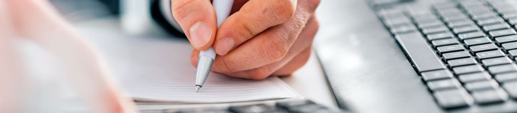 Minor in Accounting Program Page showing a mans hand writing on notebook paper. 