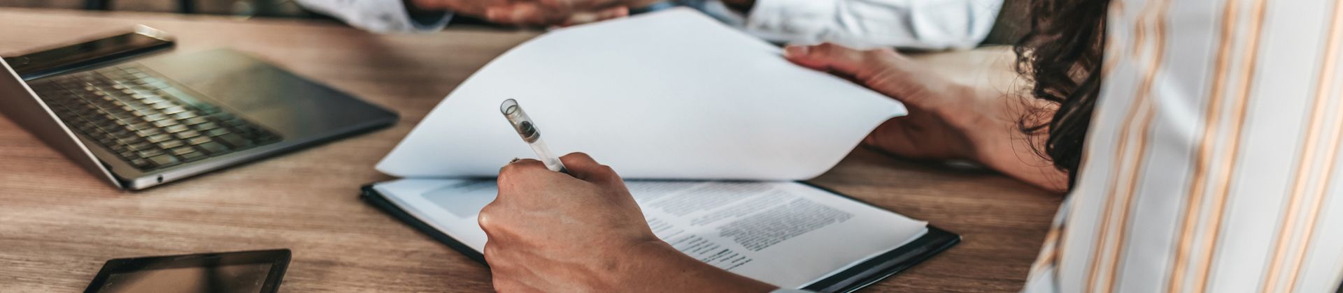 Left-hanged person writes notes on a printed page. Minor in Business Law Program Page