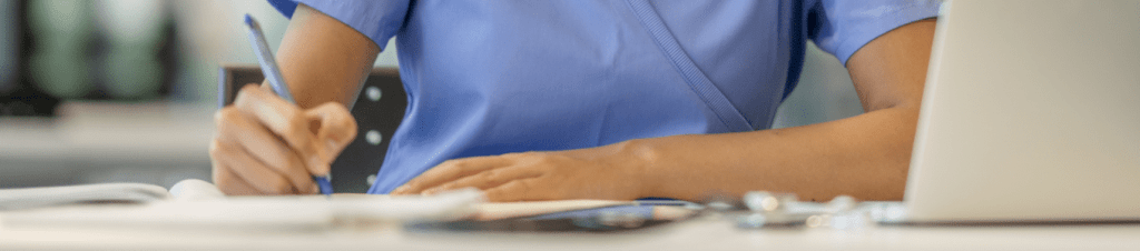 woman in scrubs writing in notebook