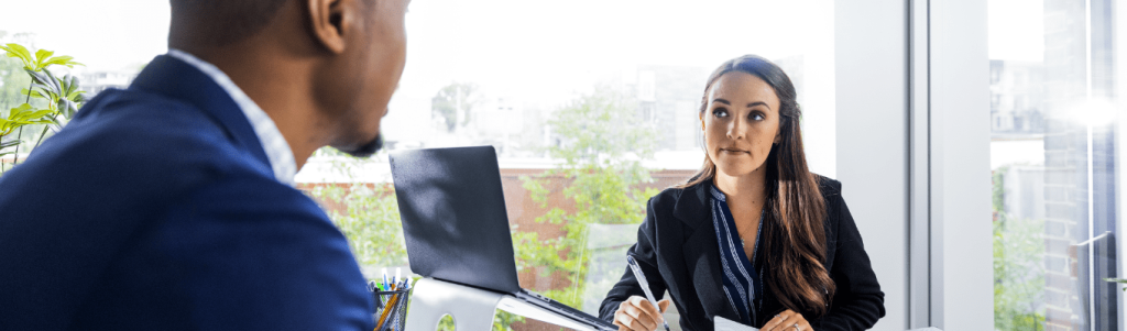 two business professionals sitting at a desk discussing a business administration degree