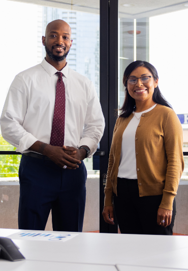two people in business casual attire stand in an office