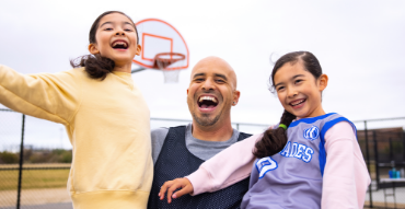 man plays on a basketball court with two kids