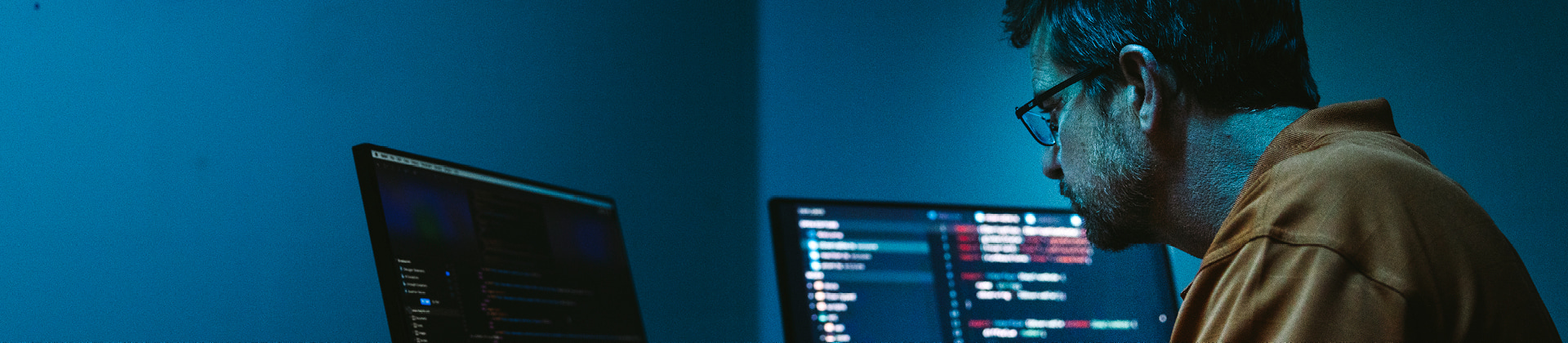 person in dark room working on computers