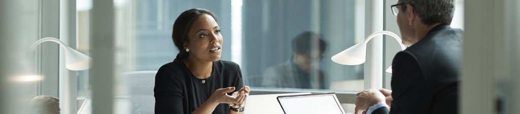 woman sitting at desk with man across from her engaged in conversation