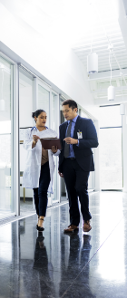 two healthcare professionals walk down a hallway talking