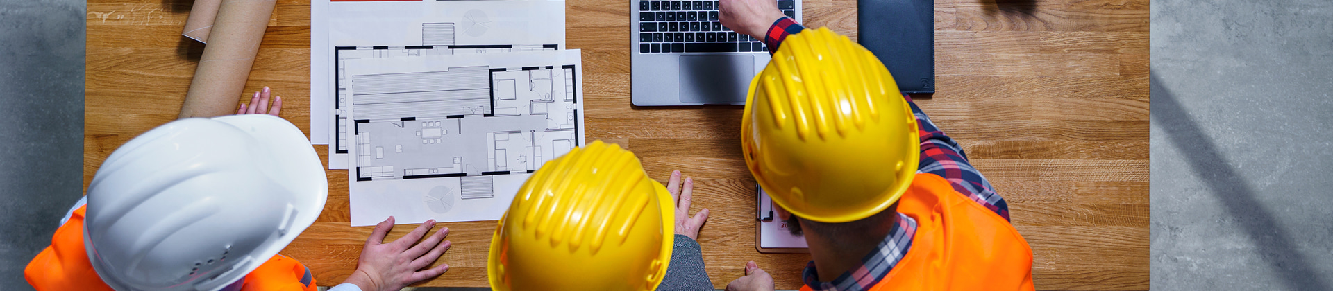 construction workers in hardhats looking at blueprints