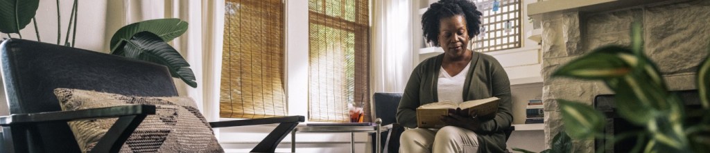 woman in chair reading a book by fireplace