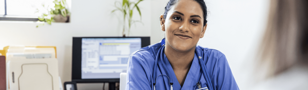 woman in scrubs smiles at a patient out of frame