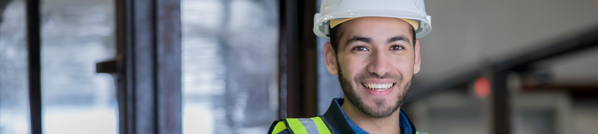 man in high-vis gear and a white hard hat smiles