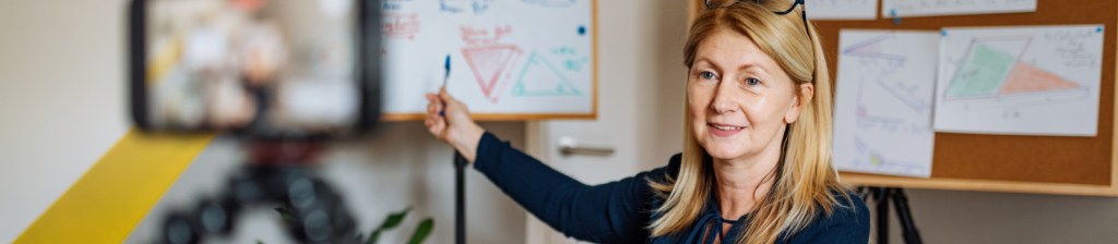 Teacher pointing to whiteboard with notes written on it