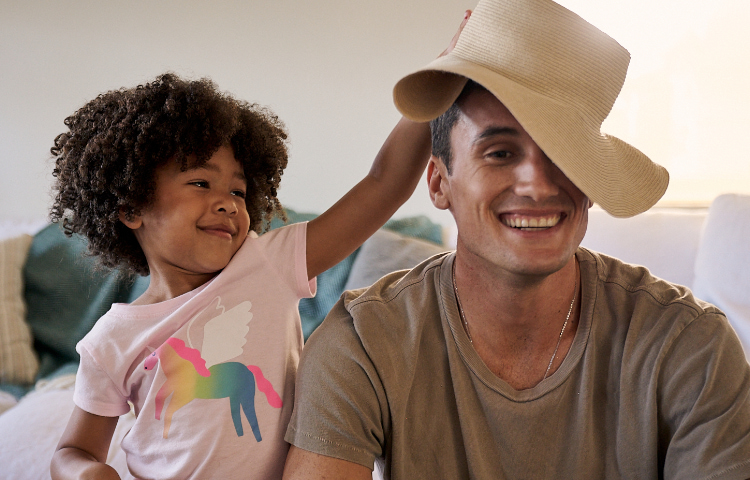 father with child putting hat on her father