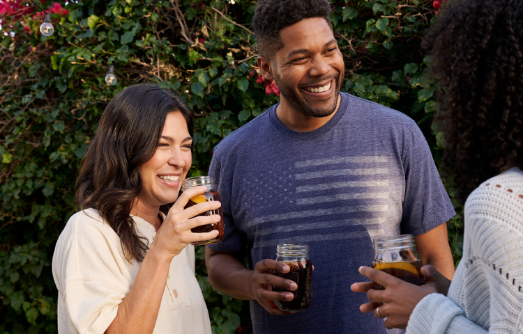 people talking and smiling in backyard bbq with America flag shirt