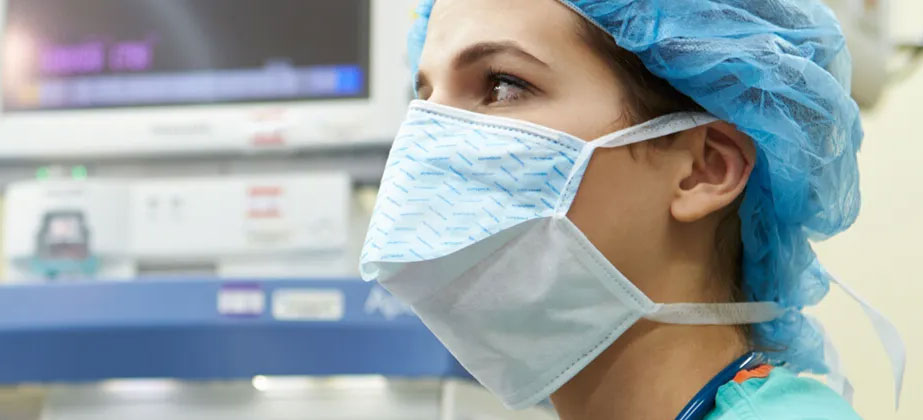 Nurse anesthesiologist in surgical room with scrubs and face mask looking on